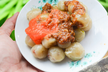 Cilok traditional tapioca snack served in a bowl with spices and herbs on a rustic wooden table selective focus on texture and presentation