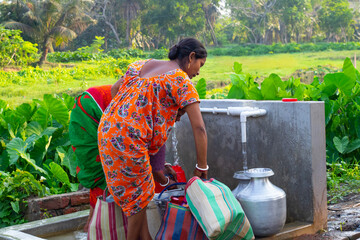 Women collects water at a rural tap in the village