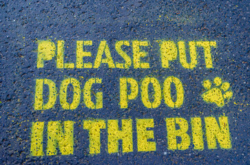Notice stenciled on the path in a public park asking people to put their dogs poo in the bin