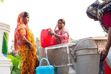 Women in colorful sarees collect water at a village tap
