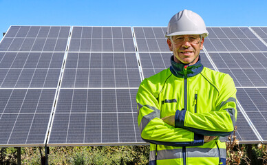Technician or engineer with crossed arms and PPE at a solar panel installation for renewable...