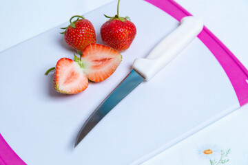 Zwei Erdbeeren und Eine mit einem Messer in zwei Teile geschnittene