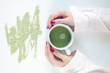 woman holding a cup of matcha. matcha latte in a white cup in hands of a woman.
