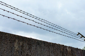 Barbed wire fence against a cloudy sky in an urban location with a hint of tension and isolation