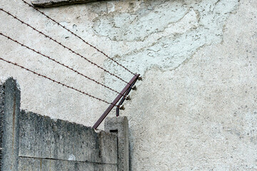 Barbed wire securing a concrete wall in an industrial area during the late afternoon in an urban...