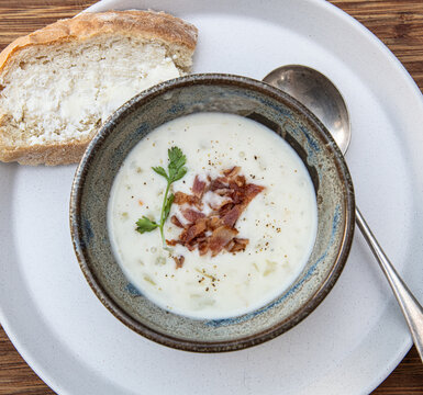 A delicious looking rustic bowl of New England Clam Chowder with a garnish of bacon and parsley.
