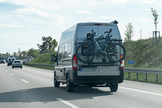 Bicycles secured on the back of a camper van traveling along a highway on a sunny day