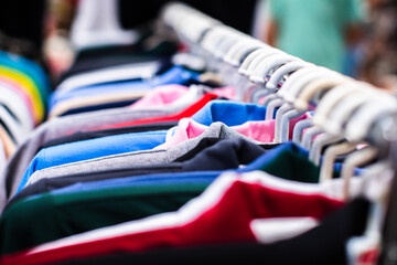 some used clothes hanging on a rack in a flea market. Collection of clothes hanging.
