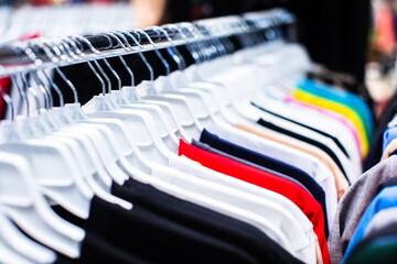 some used clothes hanging on a rack in a flea market. Collection of clothes hanging.