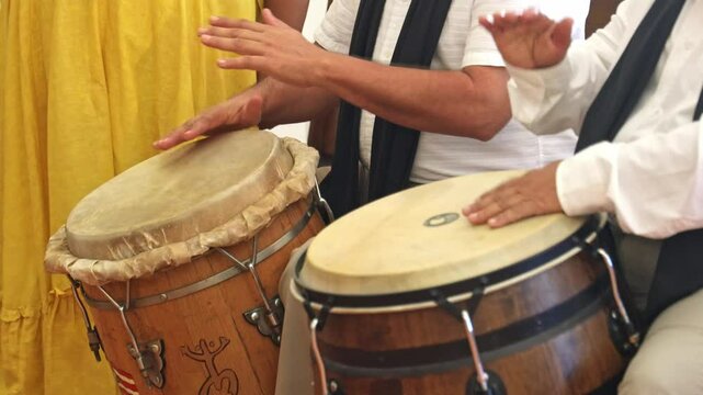 Closeup footage of two people playing congas at the church in Loiza, Puerto Rico
