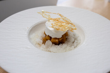 A plate of poached meringue dessert with shaved ice and cooked apples.