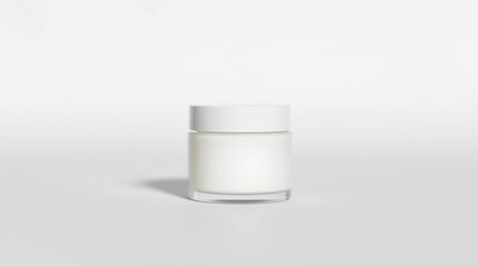 A small, white, cylindrical jar with a white lid sits on a plain white background. The jar is made of clear glass and filled with a white, opaque substance