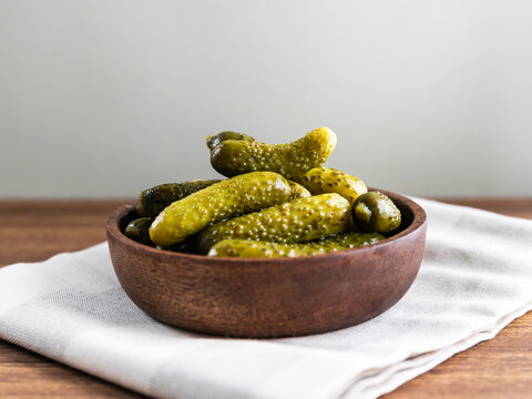 Marinated pickles or gherkins served in a wooden bowl on a table