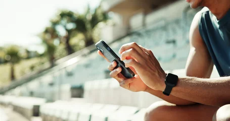 Selbstklebende Fototapeten Entspannung Athlete, hands and phone with man in stadium for running performance, fitness stats and online training plan. Closeup, workout metrics and exercise schedule with person for competition results  © peopleimages.com