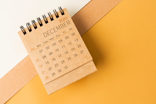 Blank desk calendar for December 2025 on brown tone background.