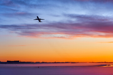 The plane takes off at dawn in heavy fog in winter. The silhouette of an airplane