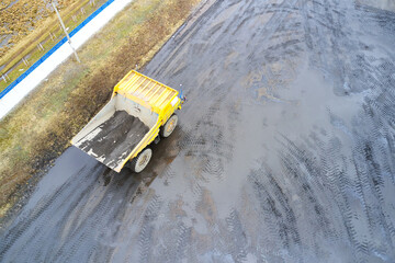 Top view of a yellow dump truck that is working on a dirty site