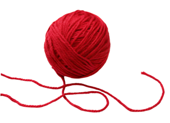 A close up of a bright red ball of yarn with loose strands against a black background studio shot