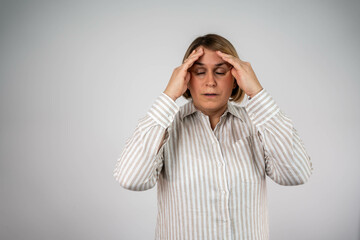 Woman overwhelmed with stress and concern, confusion and doubt, hands to head, on grey background...