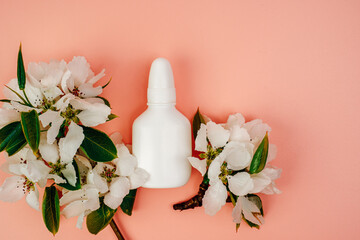 Nasal spray for allergies on a pink background. White flowers, space for text.