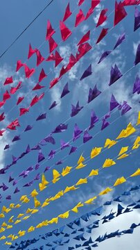 V&aacute;rios varais de barbante com bandeirolas coloridas penduradas balan&ccedil;ando ao vento, com o c&eacute;u ao fundo. Decora&ccedil;&atilde;o de festa junina.