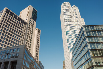 Obraz premium Low angle exterior view of the modern white curved Upper West tower and office buildings against a clear blue sky near Zoologischer Garten in Berlin Germany. 