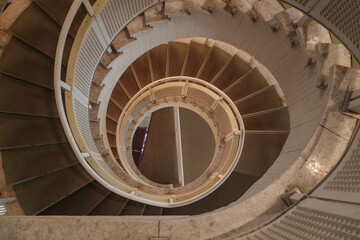 Fototapeta premium A high-angle photograph captures the mesmerizing, abstract patterns of a winding spiral staircase as it descends. 