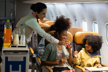 Passenger : African American sister and little girl traveling by an airplane. serving drinks. ...