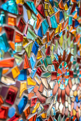 Obraz premium Colorful mosaic of glass shards on concrete wall creating vibrant patterns with reds, blues, greens, and yellows in dynamic composition.
