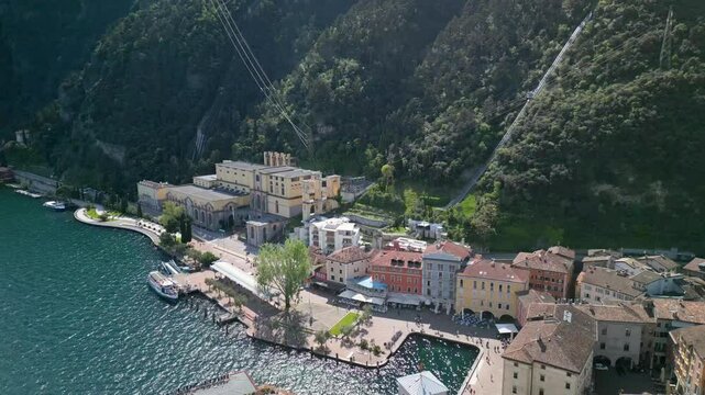 4K drone footage of Centrale Idroelettrica del Ponale near Riva del Garda, Italy. Scenic view of hydroelectric power station, cable car, colorful buildings, and mountains on Lake Garda.