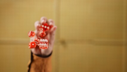 A Hand Tossing Multiple Red Dice Below the Glass Table