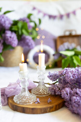 a bouquet of lilacs in a wicker basket. Romantic atmosphere on a lilac background with candles. Festive table setting