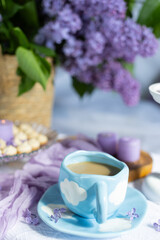 a cup with a hot drink. Breakfast with waffles and cakes, a bouquet of lilacs in a wicker basket