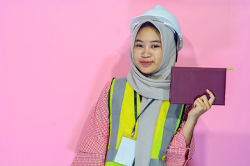 Young Asian woman an attractive young female construction worker working. Carrying a map, construction worker helmet and safety vest