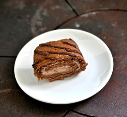 Chocolate Swiss Roll Cake in a small plate on black metal background
