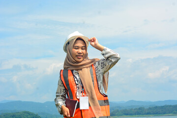 A female fish farm manager wears a safety vest and carries a book to check the work.