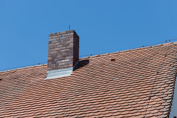 Brick Chimney on Tiled Roof Against Blue Sky