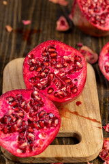cut pomegranate on a table , sweet red pomegranate cut into pieces during cooking, close up