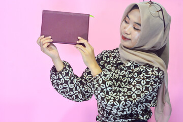 Portrait of a muslim schoolgirl carrying books in her hands and wearing a black backpack on an isolated background