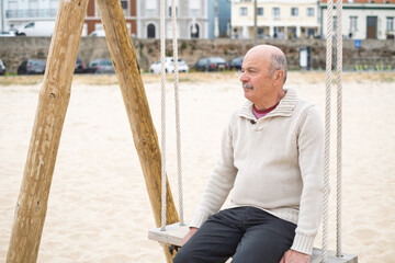 Elderly Man Sitting on a Swing at the Beach Reflecting on Life
