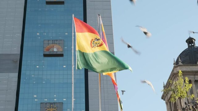 bolivian flag and whipala waving in slow motion with the wind in the city of la paz - bolivia