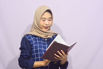 Portrait of a muslim schoolgirl carrying books in her hands and wearing a black backpack on an isolated background
