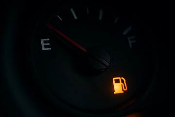 Car dashboard warning with empty fuel gauge and glowing alert light