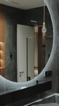 Vertical screen: modern bathroom in gray tones with minimalistic sink and mirror with illumination