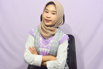 Young asian muslim woman standing with confidence, pointing gesture against purple isolated background