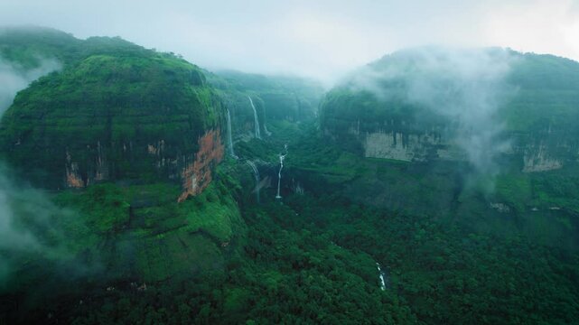 4K Aerial view of Dramatic monsoon clouds on Sahyadri hills. Devkund waterfall as seen from Savlya ghat view point. Rainy days landscape in Maharashtra, India. Waterfall flowing in mountain after rain