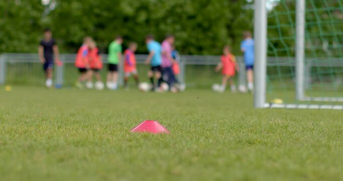 A group of enthusiastic youth soccer players are engaging in training exercises on a wellmaintained field, with colorful practice cones and goalposts set up in the background - Powered by Adobe