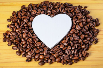 White heart decoration placed among scattered coffee beans
