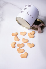 Heart shaped cookies next to a circular white box with a metal lid_vertical.
