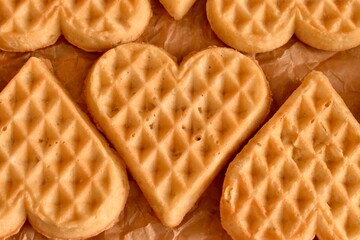 Heart-shaped Belgian waffles arranged in a row on parchment paper. Fresh, soft, golden — perfect for breakfast or dessert.